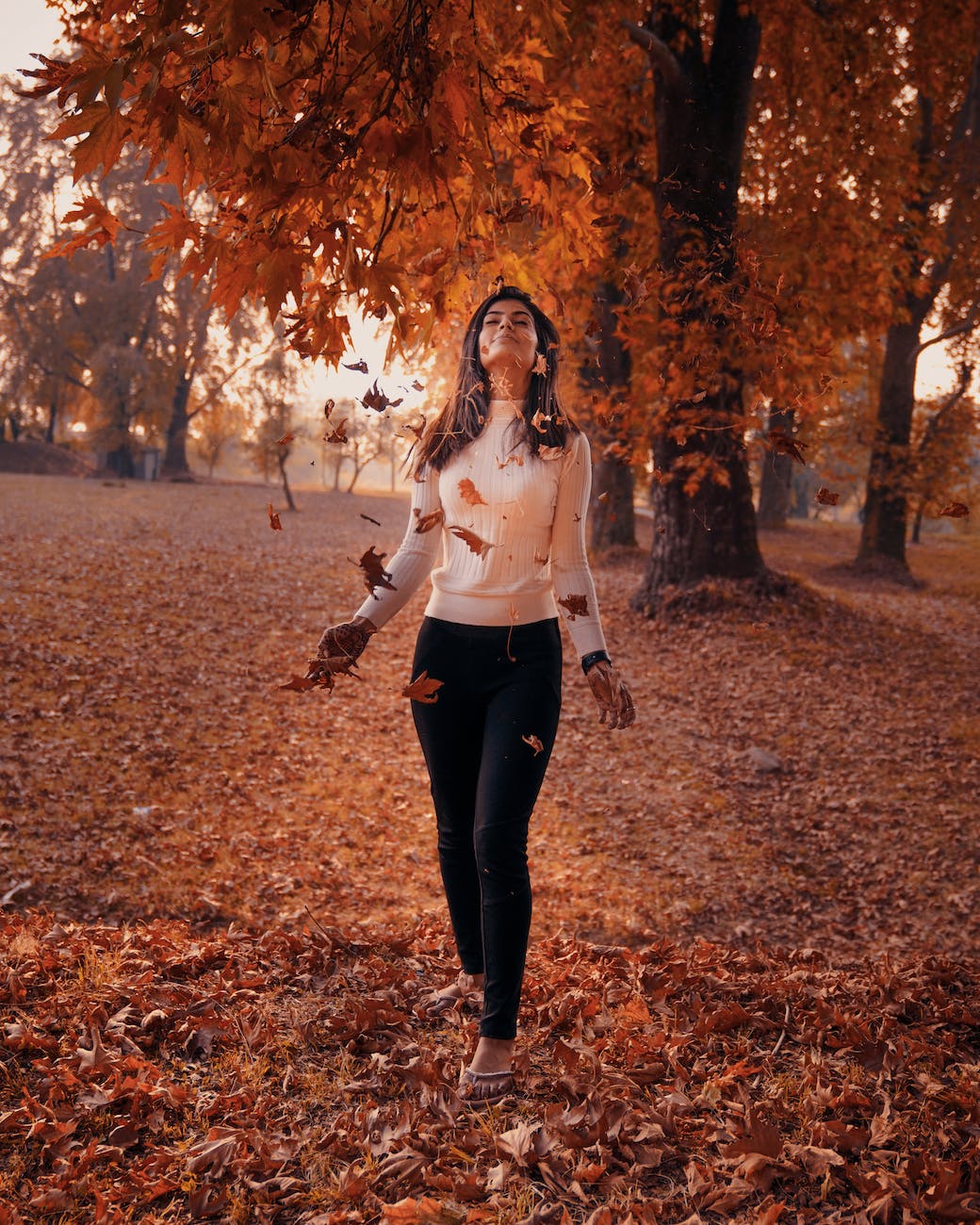 photo of a woman near falling leaves